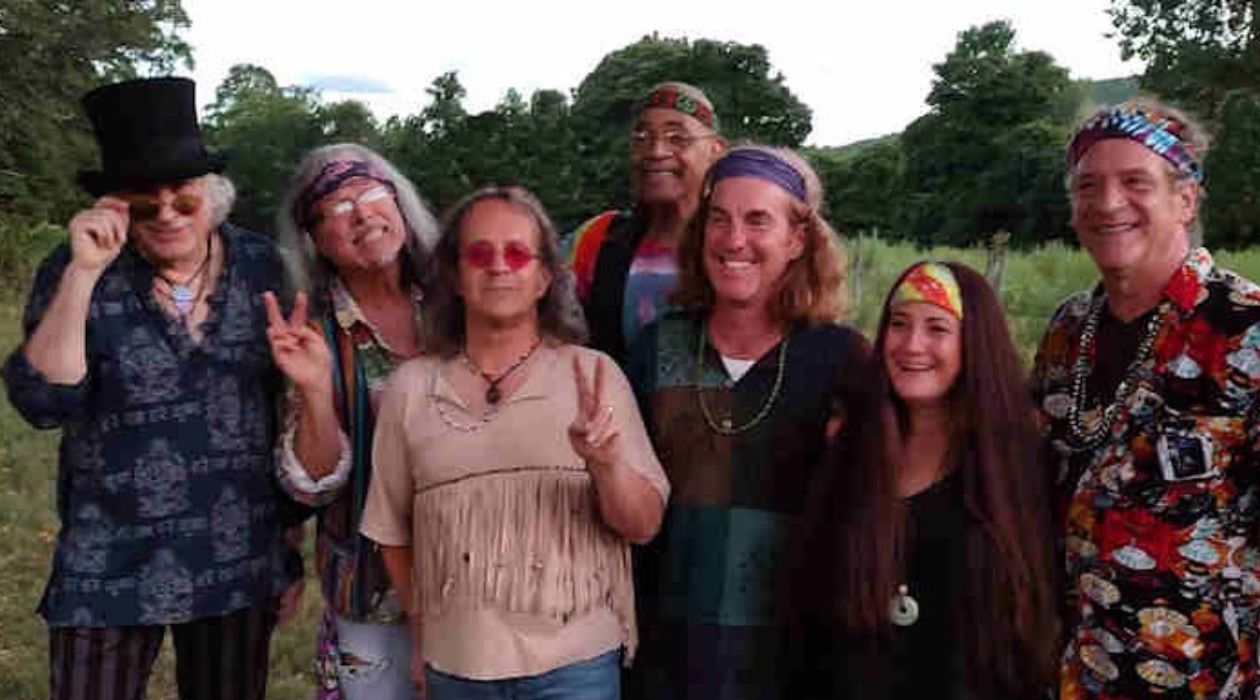 The seven member Woodstock tribute band called Back to the Garden 1969 with their long hair and wearing their signature hippie garb, including head bands, necklaces with beads and round framed sunglasses.